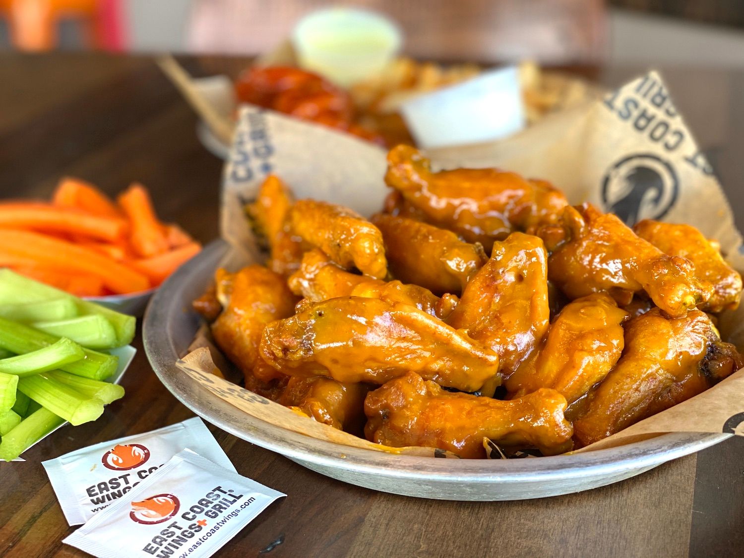 A basket of East Coast Wings + Grill wings served with celery, carrots and dipping sauce